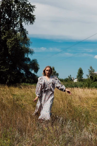  Uzun kır elbiseli genç bir kadın tarlada koşuyor.