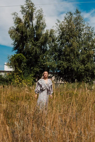  Kırsal bir elbise giymiş genç bir kadın köydeki bir tarlada rahatça yürüyor.