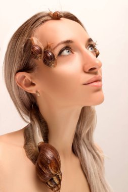 Geniş ve küçük achatina salyangozları genç bir kızın yüzünde ve boynunda sürünüyor.