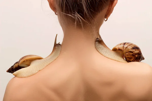 Two large achatina snails crawl over the shoulders of a young woman — ストック写真