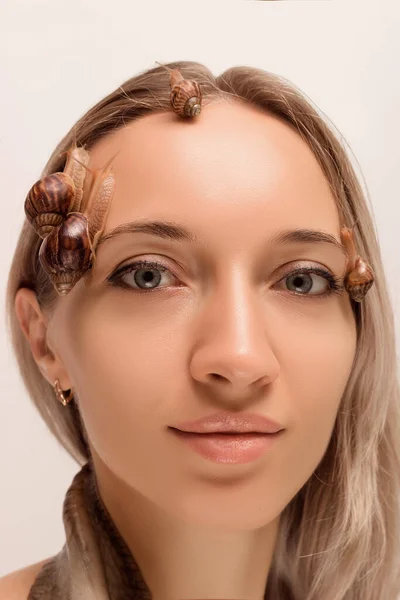 Large and small snails of achatina crawl on the face and neck of a young girl — Foto Stock