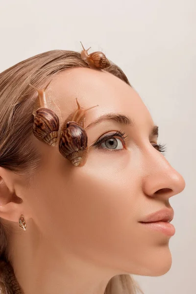 Large and small snails of achatina crawl on the face and neck of a young girl — Foto Stock