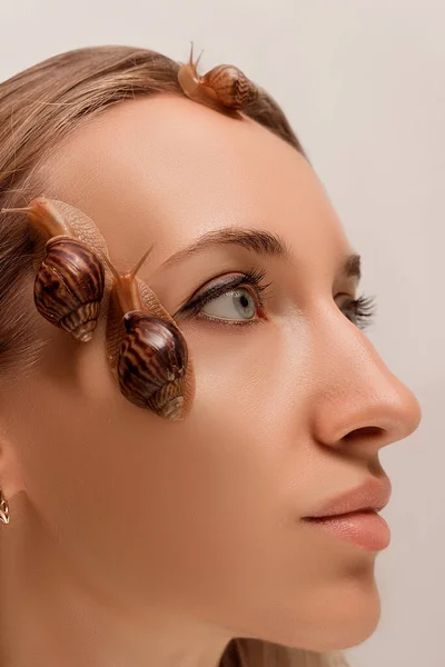 Large and small snails of achatina crawl on the face and neck of a young girl — Foto Stock