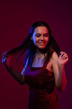 Genç ve güzel bir kız kendi elleriyle dans ediyor ve saçlarını tutuyor.