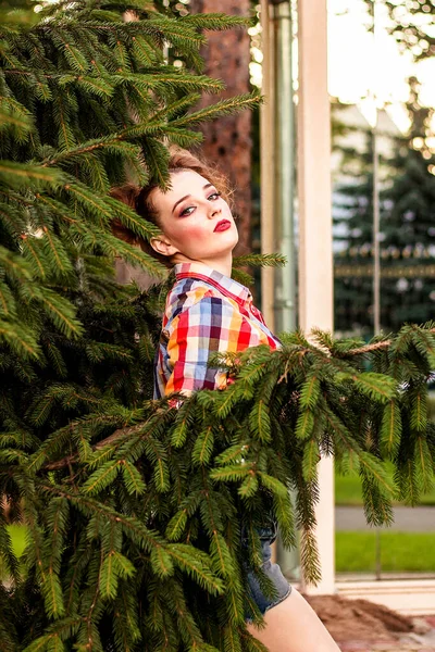 Parlak makyajlı genç seksi bir kız sırtını duvara dayıyor.