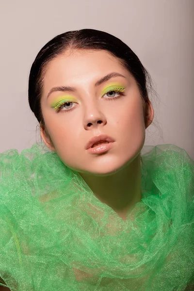 Egy gyönyörű lány arca zöld szempillákkal és szemhéjakkal. — Stock Fotó
