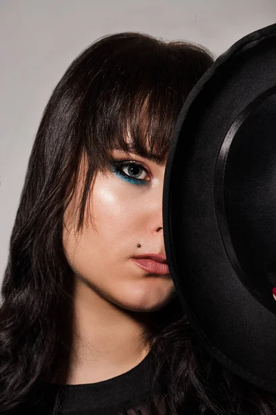 Fiatal gyönyörű barna borította fél arcát egy fekete kalap — Stock Fotó