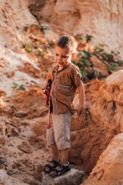 Küçük mutlu bir çocuk elinde bir daktilo tutuyor, gülümsüyor ve aşağıya bakıyor.
