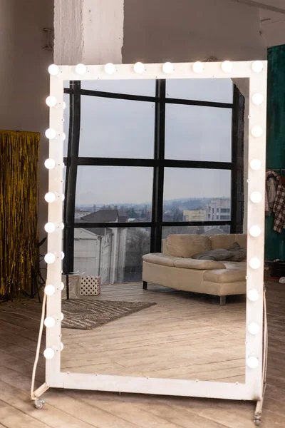 A large beautiful mirror with light bulbs stands on the floor in the interior — Foto Stock