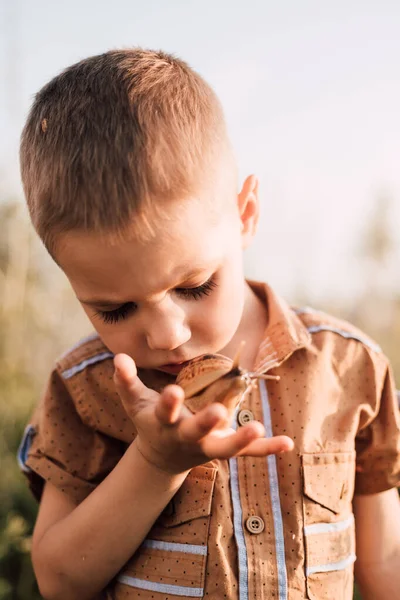 A serious little boy holds a snail in his hand in nature — Foto Stock