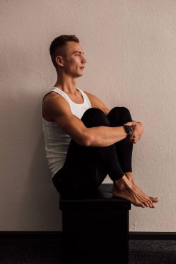 Yoga yapan bir adam elleriyle bacaklarını tutar.