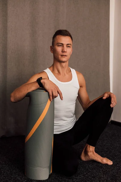 Male athlete sits in the gym leaning his hand on the carriage — стоковое фото