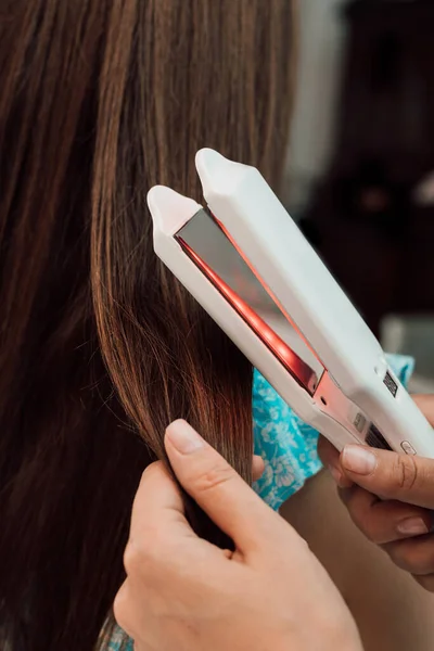 Hairdresser evens out the clients brown hair with a curler — Stock Photo, Image