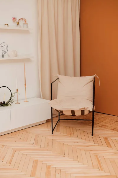 Una poltrona beige si trova in un interno luminoso vicino a una parete arancione — Foto Stock