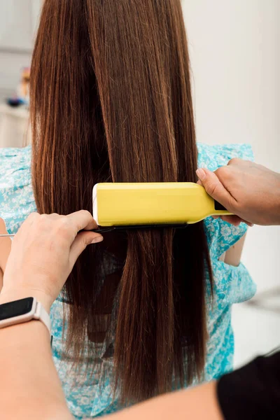 Friseur gleicht die braunen Haare der Kunden mit einem Lockenwickler aus — Stockfoto