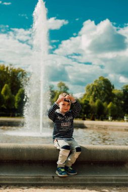Güneşli bir günde küçük bir çocuk çeşmenin yanında oturur..