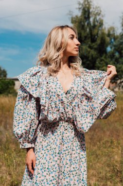 Kırsal kesimdeki bir tarlada duran, uzun kırsal elbiseli bir kadın.