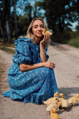 Ormanda ördek yavrularıyla mavi elbiseli güzel sarışın.