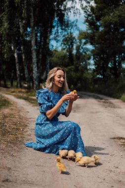 Ormanda ördek yavrularıyla mavi elbiseli güzel sarışın.