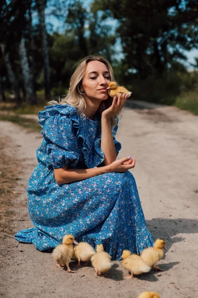 Linda jovem loira em um vestido azul na floresta com patinhos — Fotografia de Stock