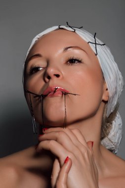 Genç kuaför topukluları ağzında tutuyor ellerine yüzüne dokunuyor.