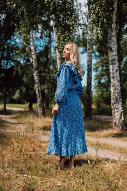 Çıplak ayaklı bir kadın. Kırsal tarzda. Arka planda Birch Grove var. Güzel sarışın.