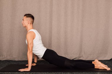 Yan görüş. Adam elleri dinlenirken yerde yatar. Sporcuların kollarındaki kaslar açıkça görülüyor.