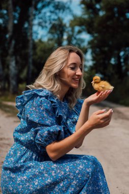 Ormanda bir kız ördek yavrularının yanına oturdu. Kırsal stil fotoğrafçılık