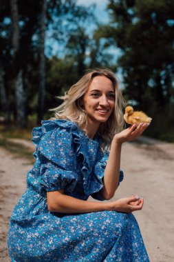 Ormanda bir kız ördek yavrularının yanına oturdu. Kırsal stil fotoğrafçılık