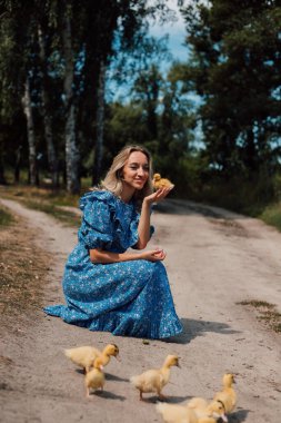 Ormanda bir kız ördek yavrularının yanına oturdu. Kırsal stil fotoğrafçılık
