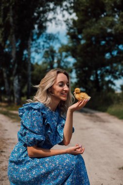 Ormanda bir kız ördek yavrularının yanına oturdu. Kırsal stil fotoğrafçılık