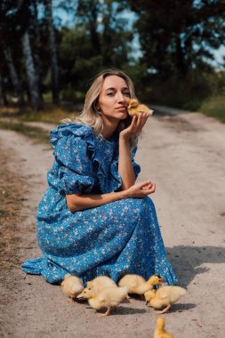 Ormanda bir kız ördek yavrularının yanına oturdu. Kırsal stil fotoğrafçılık