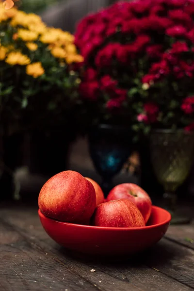 Four red apples lie in an orange plate on a wooden table. High quality photo