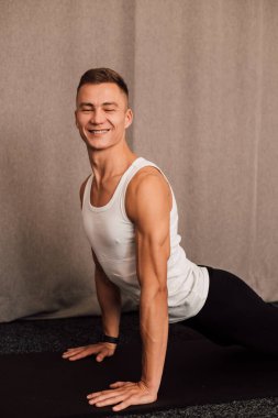 Yan görüş. Adam elleri dinlenirken yerde yatar. Sporcuların kollarındaki kaslar açıkça görülüyor.