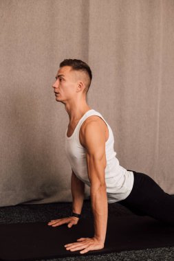 Yan görüş. Adam elleri dinlenirken yerde yatar. Sporcuların kollarındaki kaslar açıkça görülüyor.