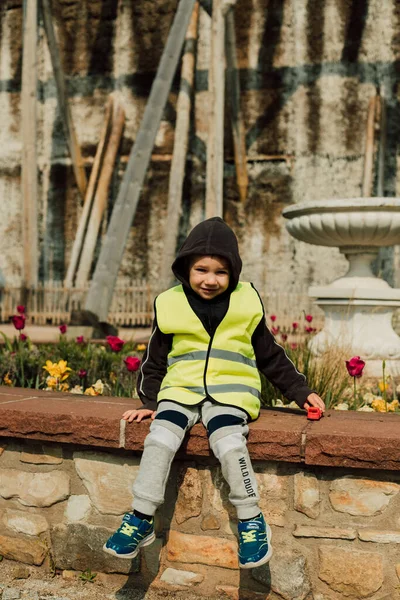 A little boy sits on a bench on a sunny day. High quality photo