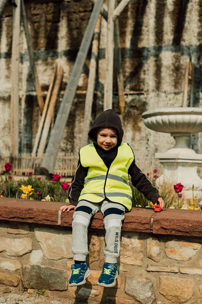 A little boy sits on a bench on a sunny day. High quality photo