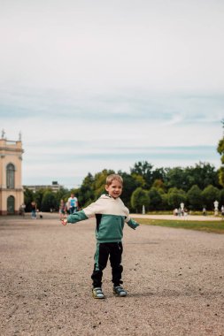 A little boy in a tracksuit stands on a large square in Europe. High quality photo