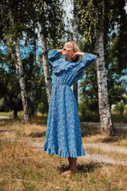 Çıplak ayaklı bir kadın. Kırsal tarzda. Arka planda Birch Grove var. Güzel sarışın.