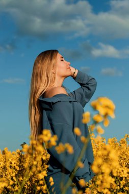 Kız yana doğru duruyor. Bir el saçına dokunuyor. Onun gözleri kapalı. Baş yukarı kalkıyor. Bir kadın dinlenmeyi ve doğayı sever.