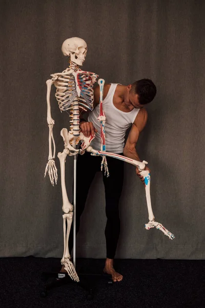 Homem Segura Uma Perna Esqueleto Nas Mãos Aponta Dedo Para — Fotografia de Stock
