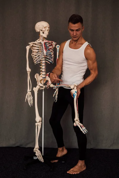 a man holds a skeleton leg in his hands and points a finger at it. High quality photo