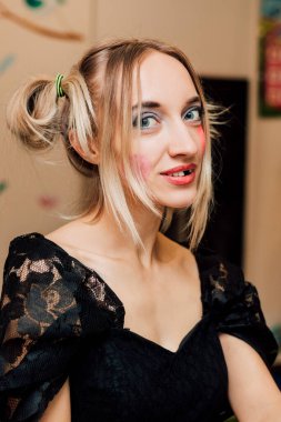 Cadı siyah guipure bir elbise ve siyah toplar giyiyor. Parlak makyaj ve komik saç stili