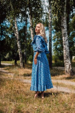 Çıplak ayaklı bir kadın. Kırsal tarzda. Arka planda Birch Grove var. Güzel sarışın.