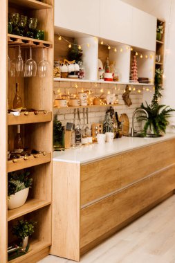 Raflarda bir sürü kap, tabak ve baharat var. Mutfak Noel çelenkleriyle, Noel ağaçlarıyla süslenmiş.