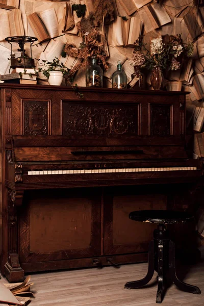 An old piano in a dark room. Lots of books on the walls. High quality photo