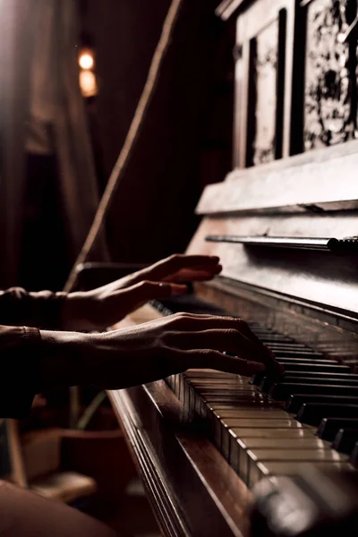 An old piano in a dark room. Lots of books on the walls. High quality photo