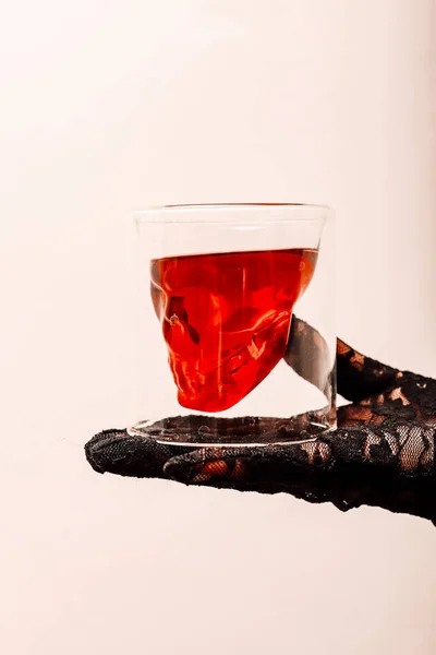Whiskey glass with a skull on the arm on a white background. Halloween. High quality photo