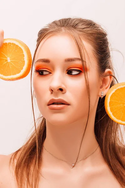 Девушка Держит Две Половинки Сочных Апельсинов Возле Лица Портрет Молодой — стоковое фото
