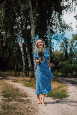 A woman in a long blue dress whirls and has fun
